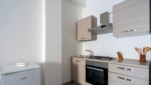 Une cuisine compacte équipée d’une cuisinière, d’un four et d’un petit réfrigérateur intégrés.