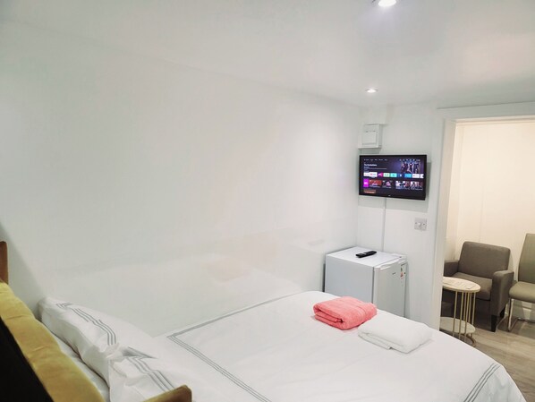 A hotel room with a bed, a TV mounted on the wall, a small table, and a chair.