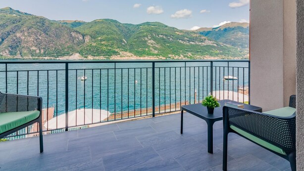 A balcony with a view of the sea and mountains, featuring outdoor furniture and a potted plant. - Ninfea Apartments by Wonderful Italy - Teal (Lezzeno)