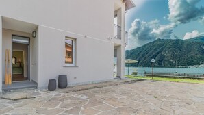 Um pátio pavimentado em pedra com vista para um lago e montanhas.