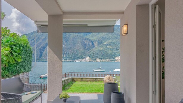 A balcony with a view of a lake and mountains, a table with chairs, and a potted plant. - Ninfea Apartments by Wonderful Italy - Arctic (Lezzeno)