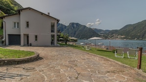 A two-story building with a stone-paved driveway and a view of a lake and mountains. - Ninfea Apartments by Wonderful Italy - Arctic (Lezzeno)