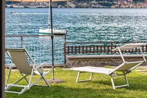 A terrace with two white lounge chairs and a metal railing overlooking a body of water with boats. - Ninfea Apartments by Wonderful Italy - Sapphire (Lezzeno)