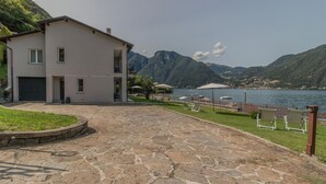 A two-story building with a stone-paved driveway and a view of a lake and mountains.