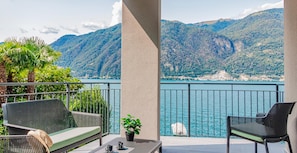 A balcony with outdoor furniture, a view of a lake, and mountains in the background. - Ninfea Apartments by Wonderful Italy - Sapphire (Lezzeno)