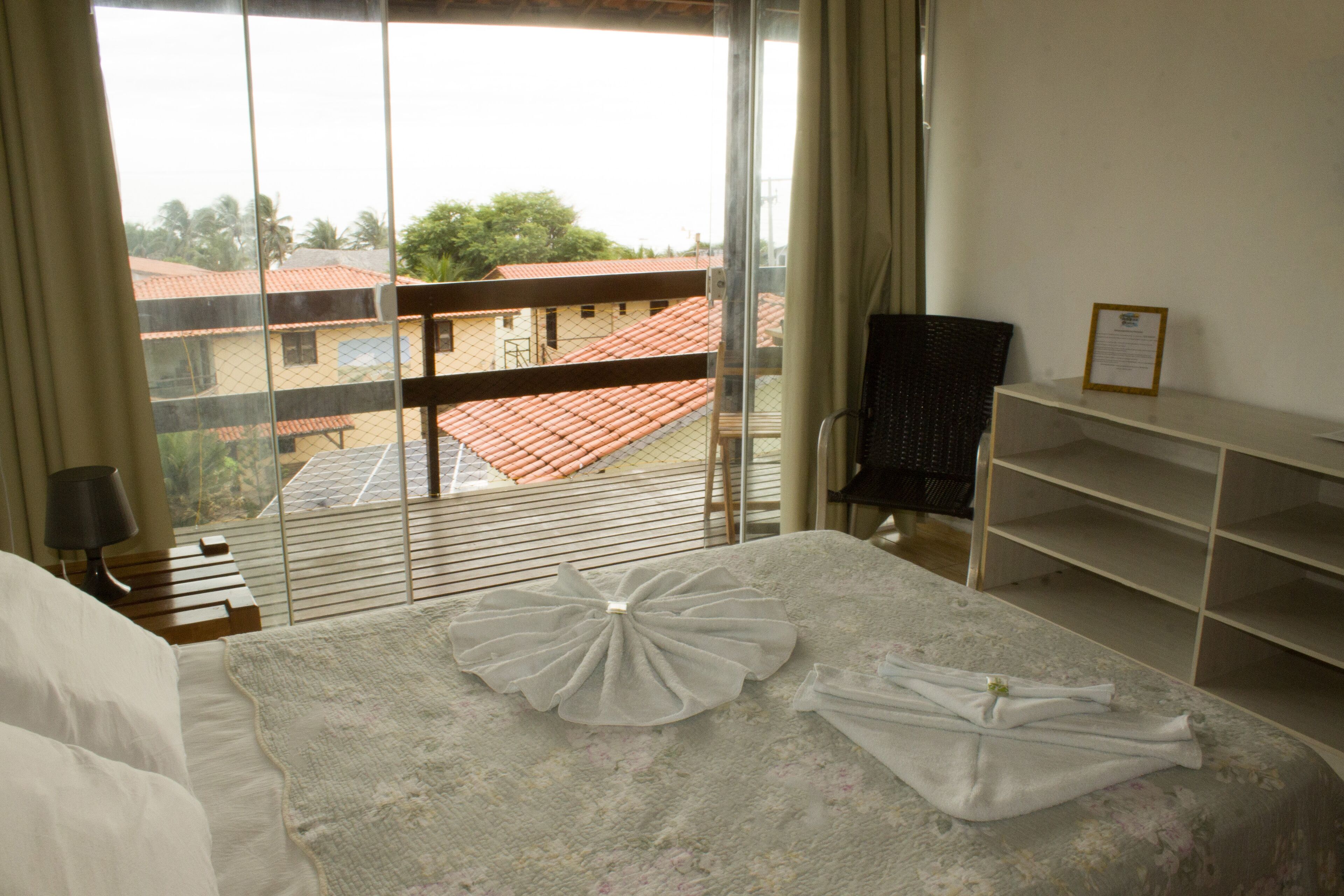 Habitación de hotel con cama, una silla, un escritorio y vista a edificios a través de una ventana.