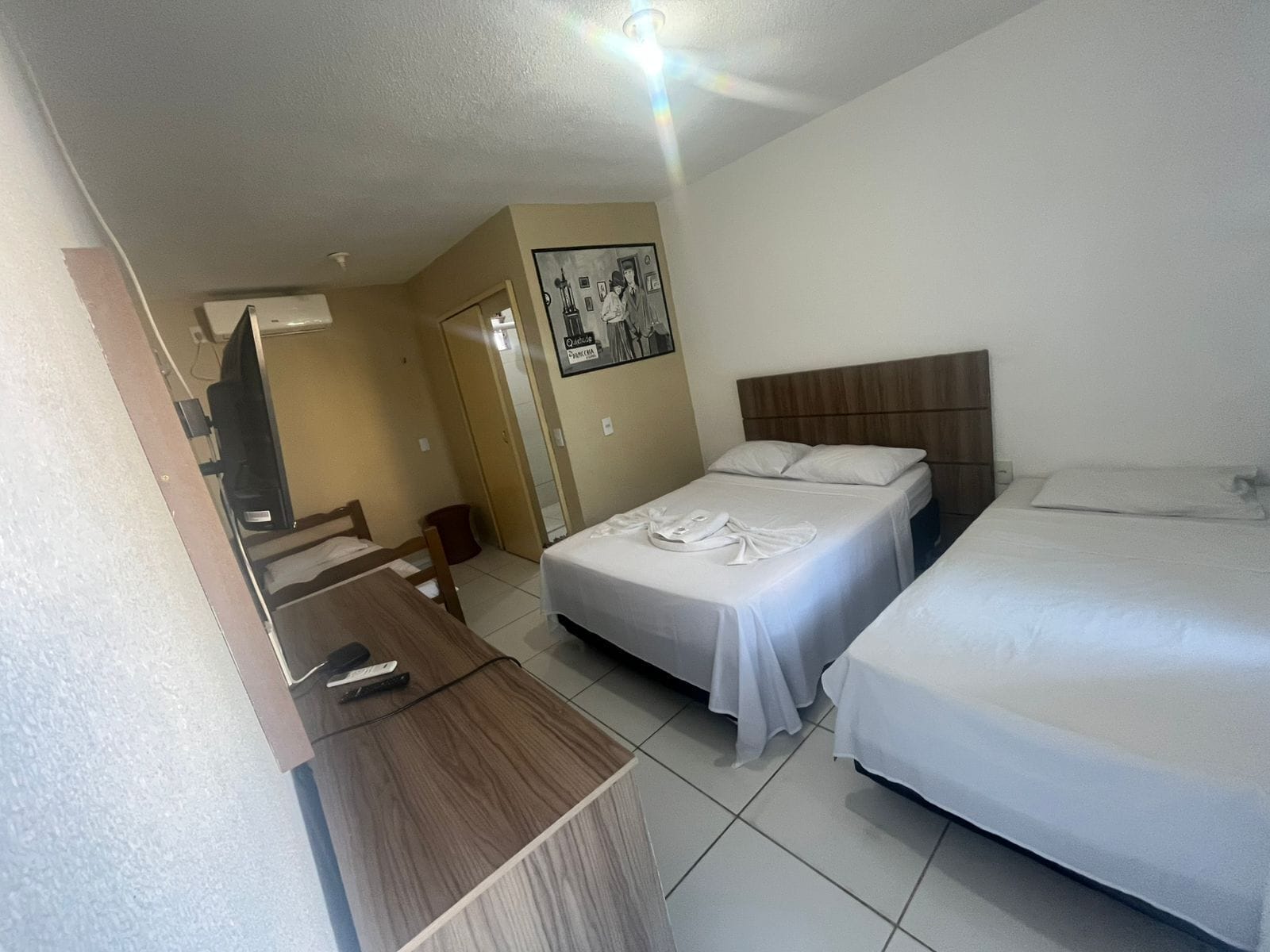 A hotel room with two beds, a desk, and a television.