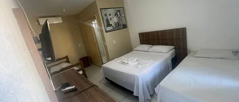 A hotel room with two beds, a desk, and a television.