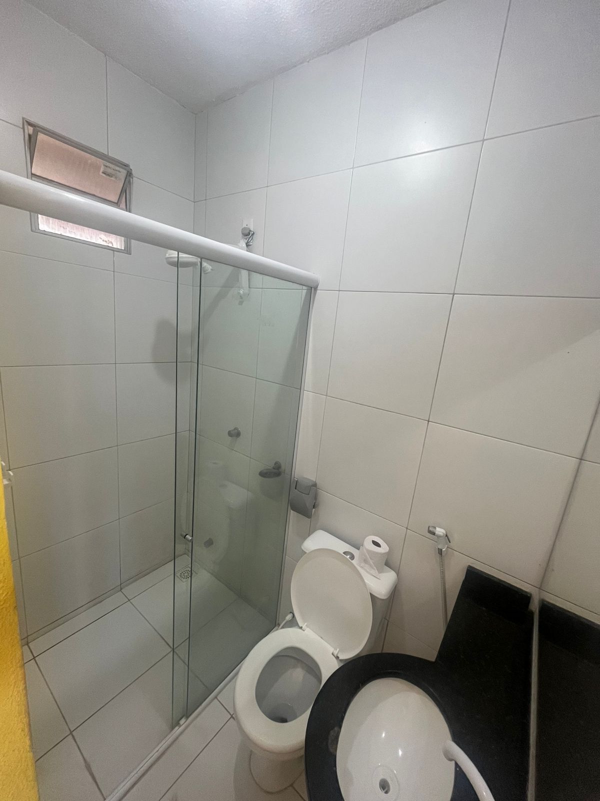 A bathroom with a glass-enclosed shower, a toilet, and a sink.