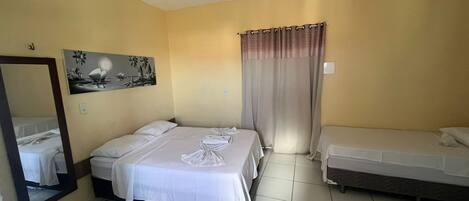 A hotel room with two beds, a large mirror, a painting, and a curtain.