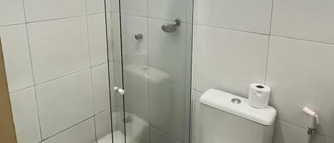 A bathroom with a glass-enclosed shower, a toilet, and a sink with a black countertop.