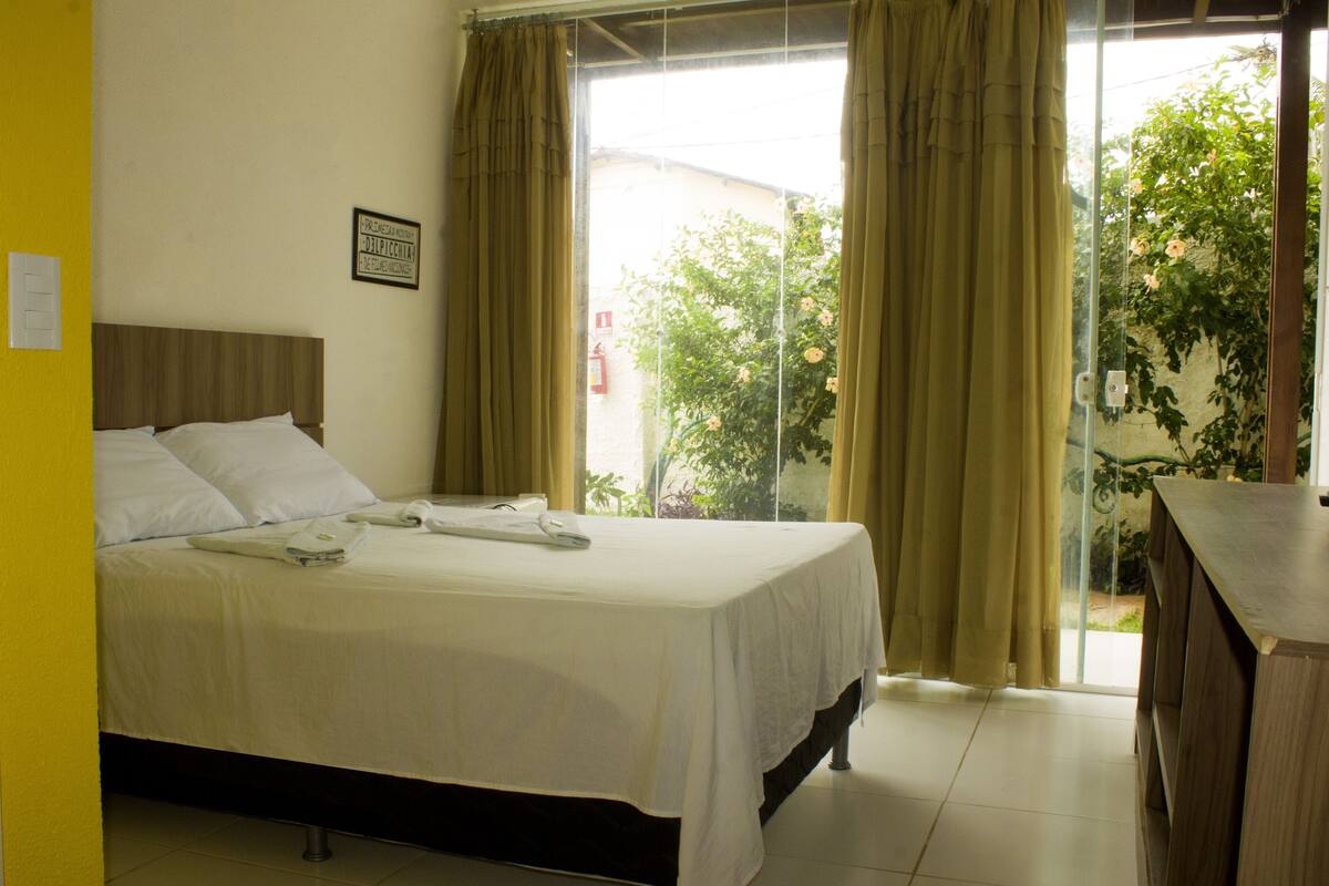 A hotel room with a bed, a desk, and a view of the outside.