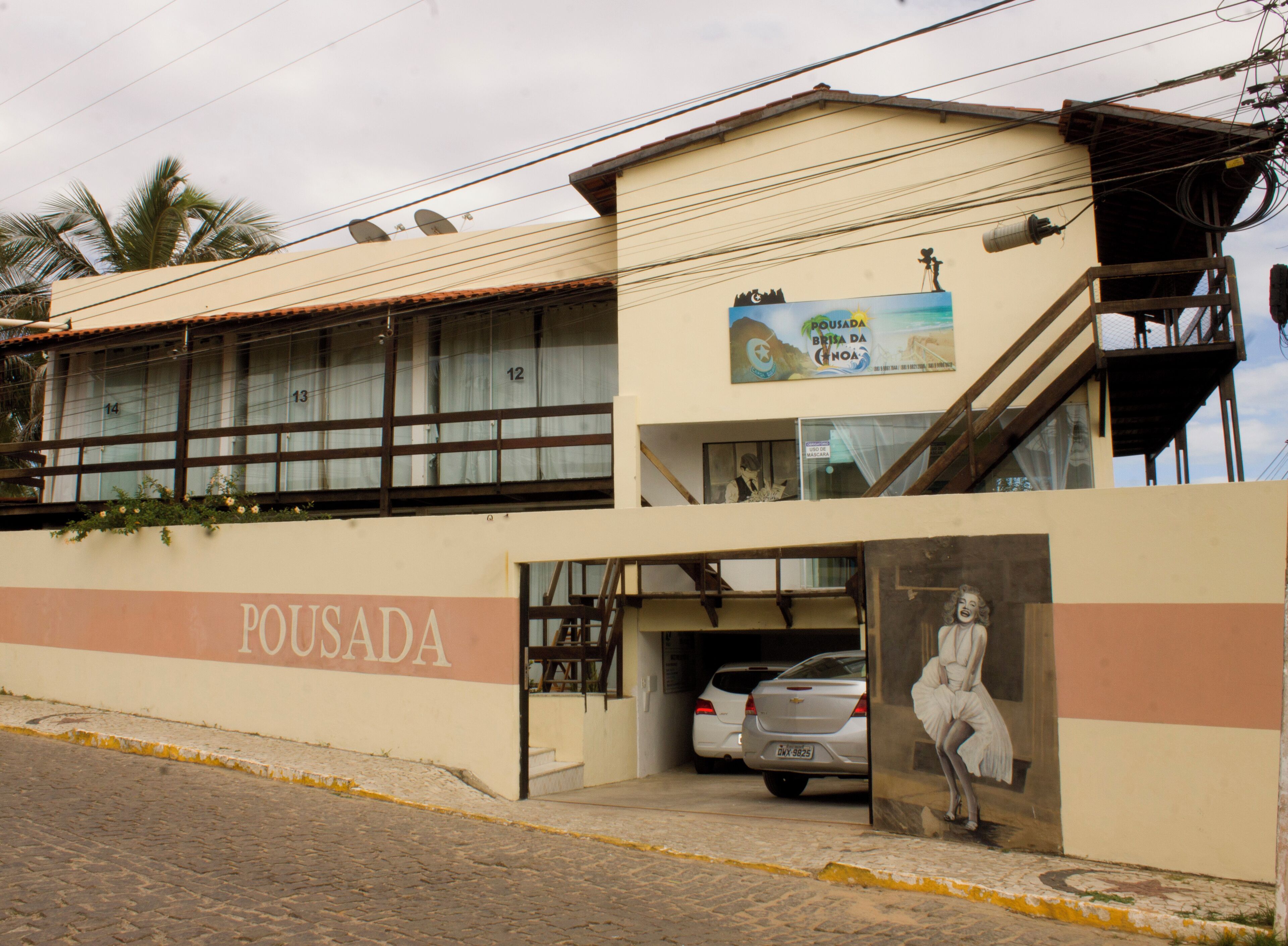 A building with a sign reading "POUSADA" and a parked car in front.