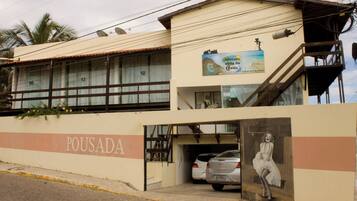 A building with a sign reading "POUSADA" and a parked car in front.