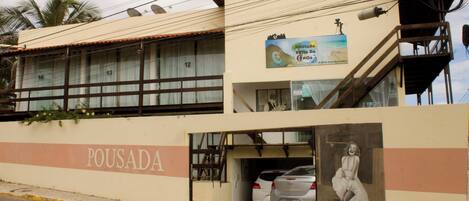 A building with a sign reading "POUSADA" and a parked car in front.