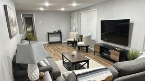 A modern living room with a grey sofa, a coffee table, a TV, and a fireplace. - HOT TUB - The Lodge - 4 bedroom home at Table Rock Lake - 2 blocks from water (Eagle Rock)