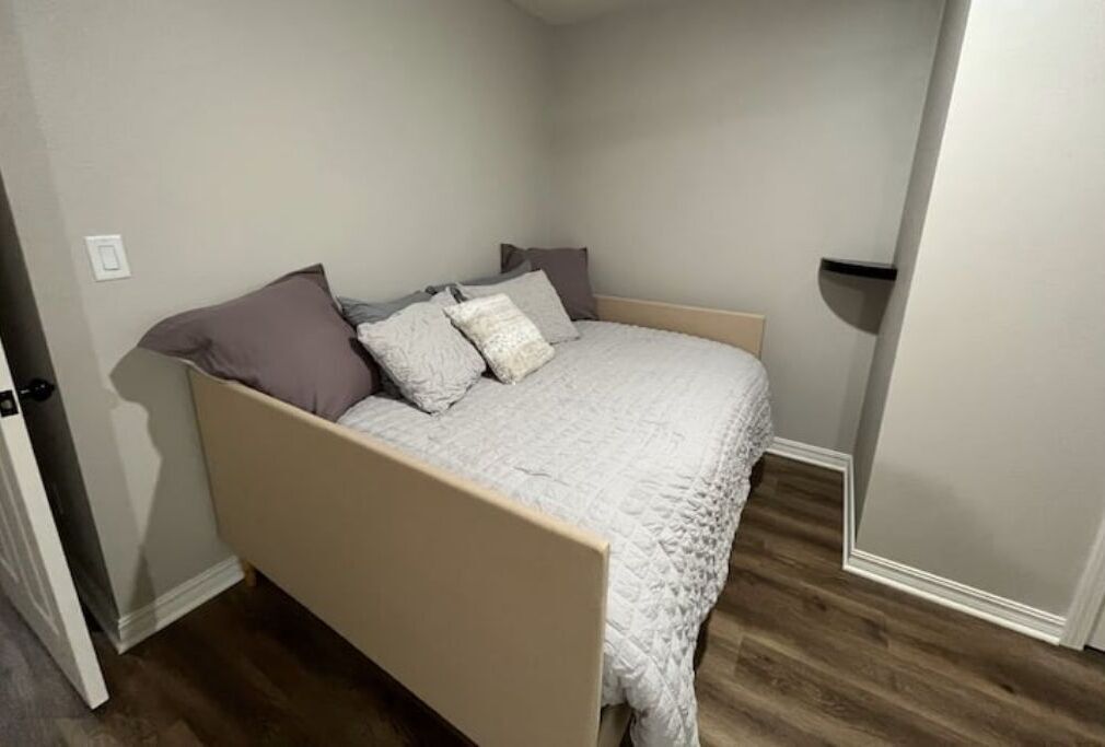 A bedroom with a bed, a door, and a wall socket.