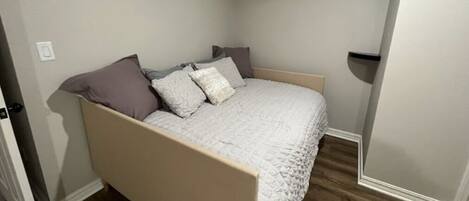 A bedroom with a bed, a door, and a wall socket.