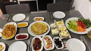 Een eettafel gedekt met diverse gerechten, waaronder friet, een quiche en een salade.
