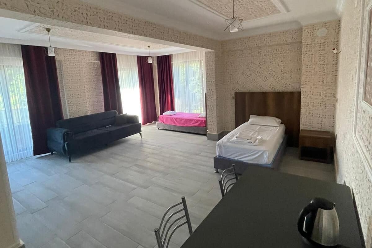 Una habitación amplia con una mesa de comedor, un sofá, una cama y un ventanal con cortinas.