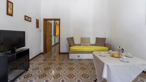 A small, clean room with a bed, a TV, a table with breakfast, and patterned flooring. - 3459 Casetta Mulino by Barbarhouse (Nardò)