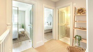 A hallway with three doors leading to different rooms, each with distinct flooring and furniture. - The Shell House - 5 mins to Town and Beach with Peaceful Garden (pet friendly) (Dorset)