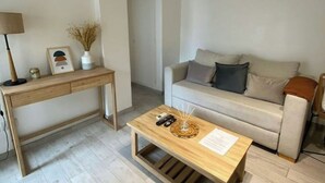 A minimalist living room with a wooden desk, a sofa, and a coffee table.
