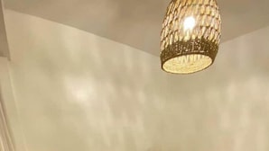A bedroom with a bed, nightstands, a bedside table, and a hanging light fixture.