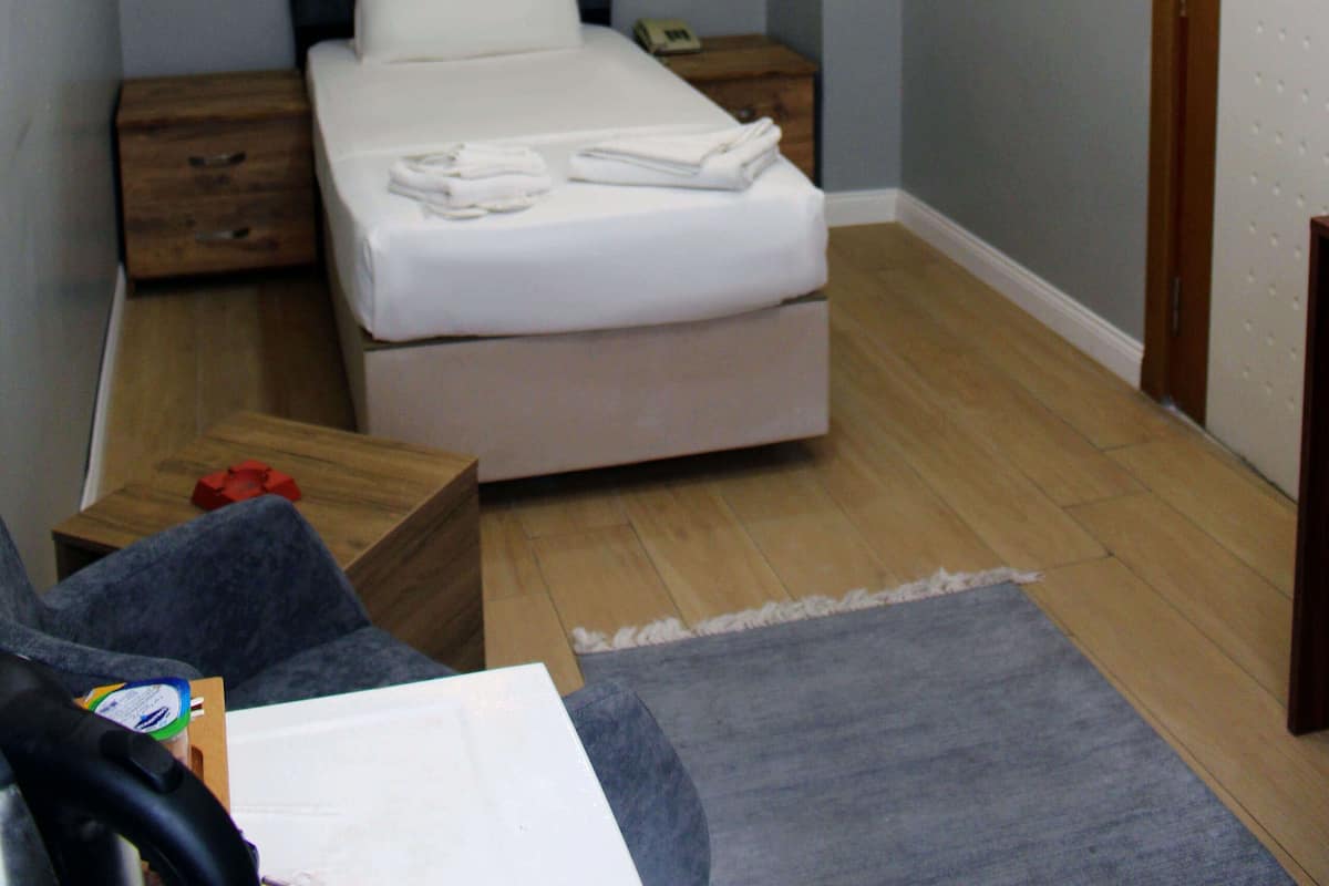 A bedroom with a bed, bedside tables, a painting, and a wooden floor.