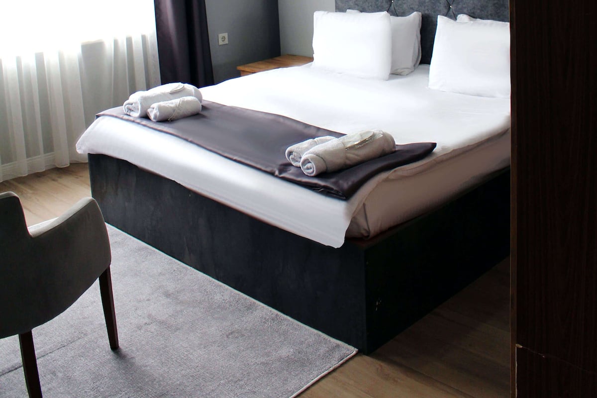 A modern hotel room with a large bed, a chair, and a painting on the wall.
