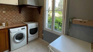 A compact kitchen with a washing machine, oven, and a dining area with a table and chairs.