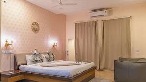 Ein Schlafzimmer mit Bett, Nachttisch, Lampe, Klimaanlage und Vorhängen.