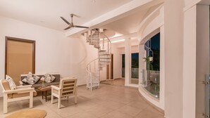 Ein großzügiger Wohnbereich mit Wendeltreppe, Deckenventilator und Blick ins Freie.