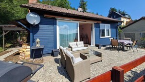 Une maison bleue dotée d’un patio aménagé avec des meubles en osier, un barbecue et une antenne parabolique.