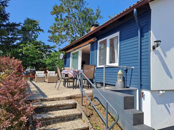 Una casa azul con un porche, mobiliario exterior y una escalera que lleva a la entrada.