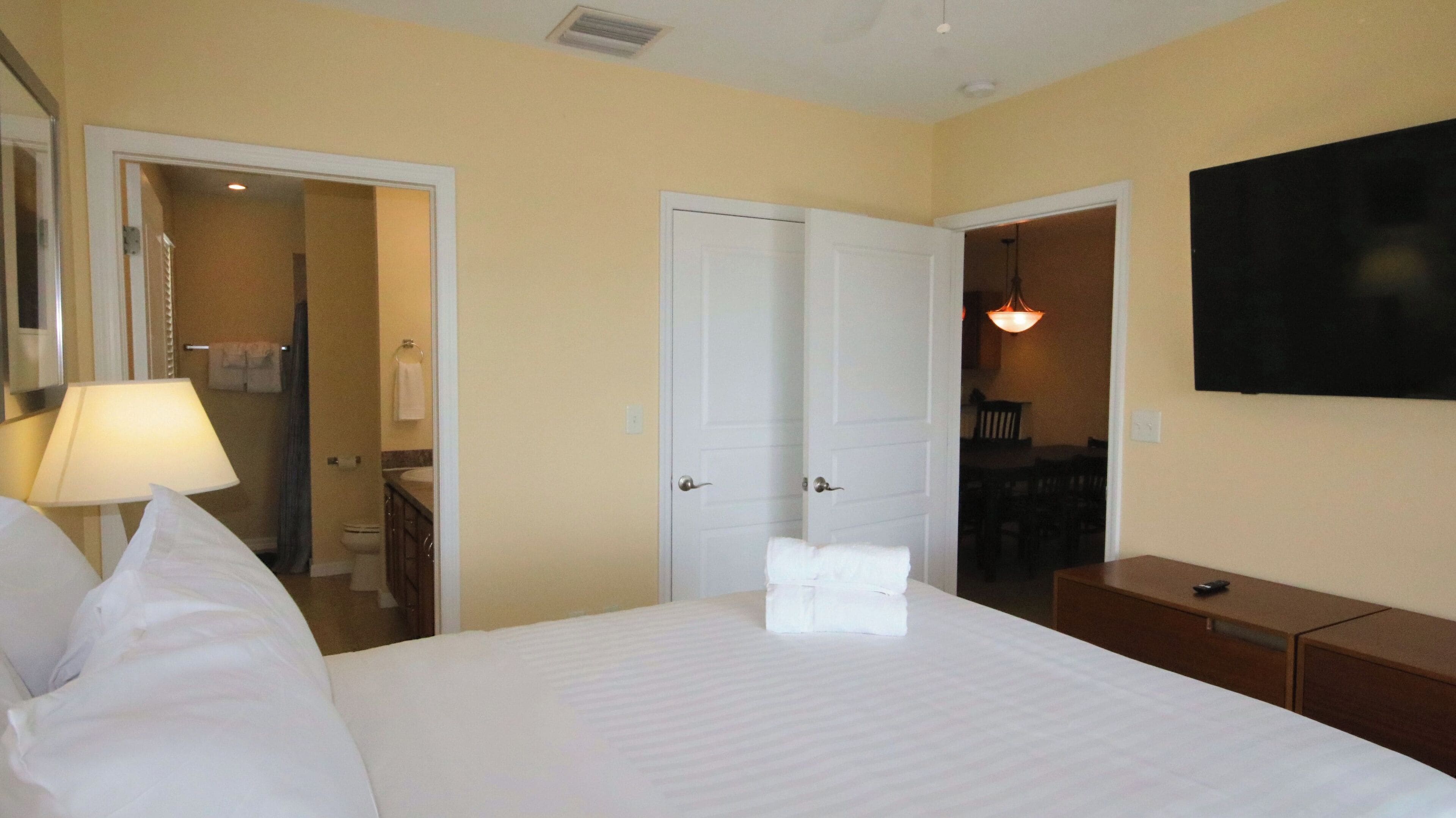 Una camera d'albergo con un letto, una scrivania, una sedia, una televisione e un bagno visibile attraverso una porta aperta.