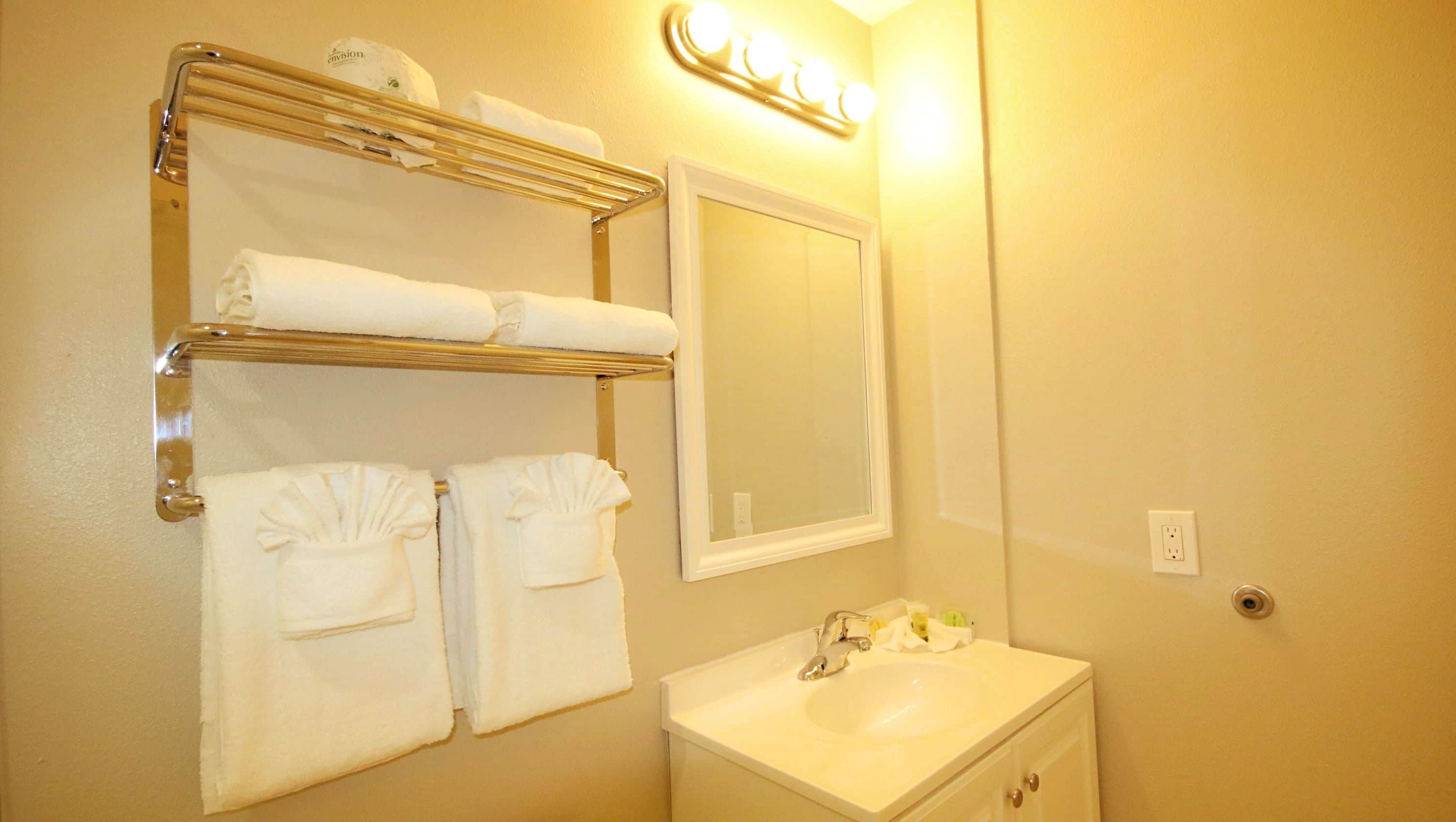 A bathroom with a sink, mirror, towel rack, and a light fixture.