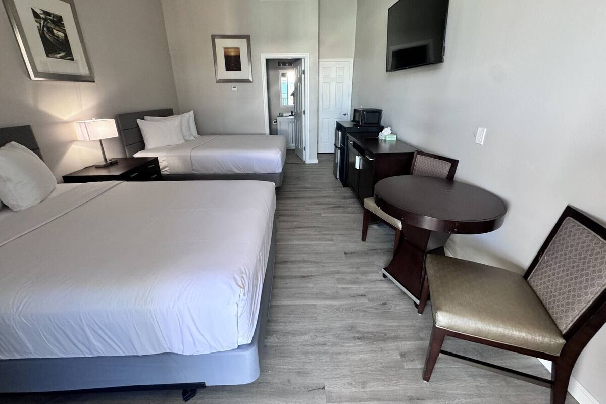 Habitación de hotel con dos camas, un escritorio, una televisión y un comedor.