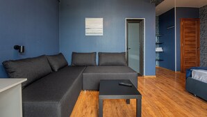 A modern living room with a sectional sofa, a small table, and a wooden floor. - Hotel Villa Lapa (Telavi)
