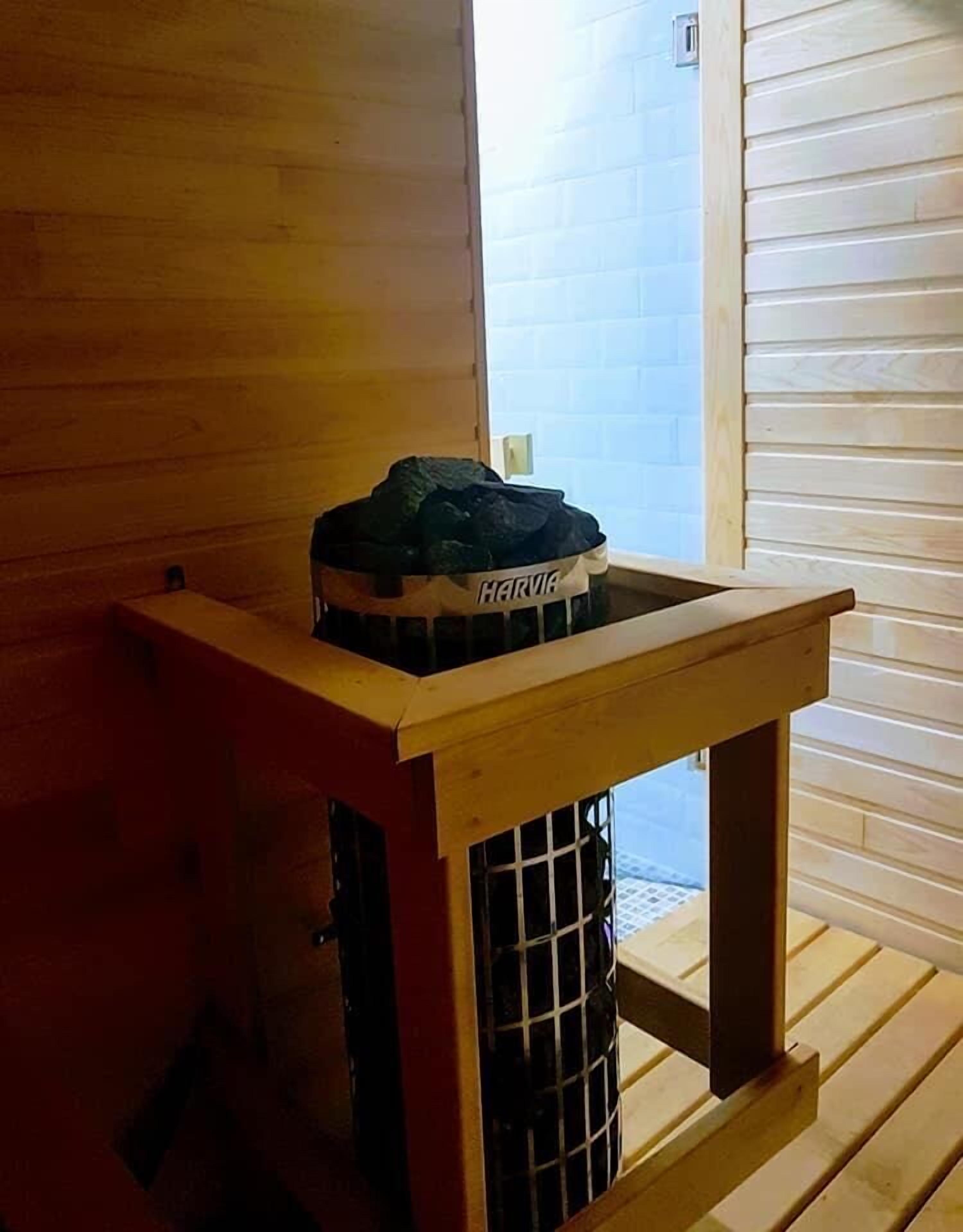 A wooden bench with a metal grill, a Harvia bag on top, and a door leading to an outdoor area.