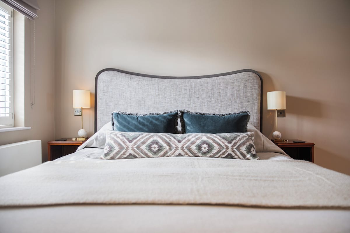 A neatly made bed with a patterned pillow and two bedside lamps on wooden nightstands.