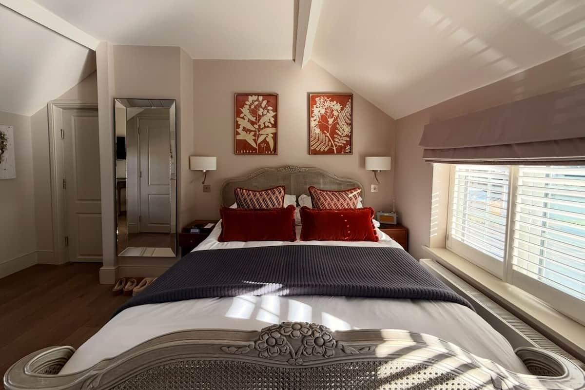 A bedroom with a large bed, a wardrobe, a mirror, and two wall-mounted lamps.
