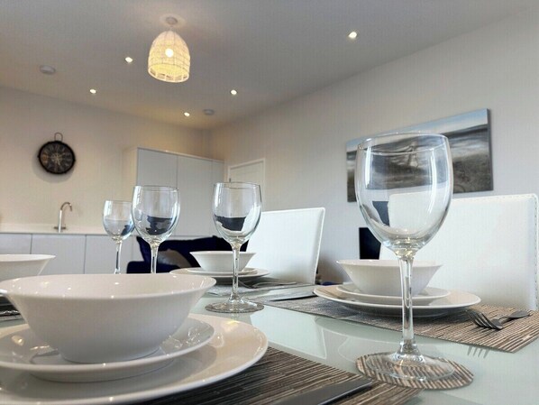Un coin repas avec une table dressée pour quatre personnes, comprenant des bols, des assiettes et des verres à vin.