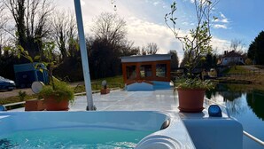 A swimming pool with a hot tub, surrounded by potted plants and a small building. - Au fil de Leau (Plobsheim)