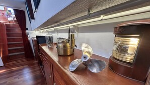 A kitchen with wooden cabinets, a stainless steel kettle, a coffee maker, and a metal propeller on the counter. - Au fil de Leau (Plobsheim)