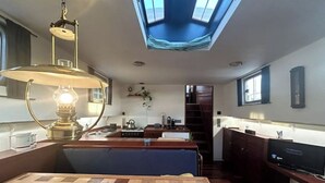 A compact kitchen with a central island, a dining table, and a built-in TV. - Au fil de Leau (Plobsheim)