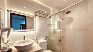 Un baño moderno con ducha envuelta en vidrio, un lavabo grande y un inodoro.