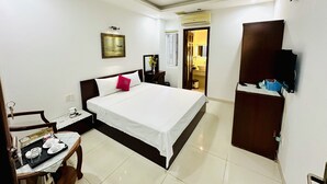 Habitación de hotel con cama, mesita de noche, silla y un pequeño comedor con una bandeja de platos.