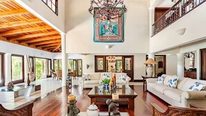 A spacious living area with high ceilings, large windows, and a central coffee table with decorative items.