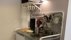 Cozinha compacta com micro-ondas embutido, pia e bancada pequena.